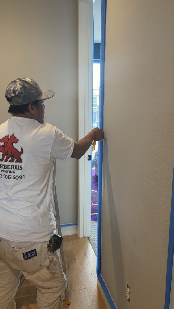 Cerberus Home painter masking a doorway edge before painting