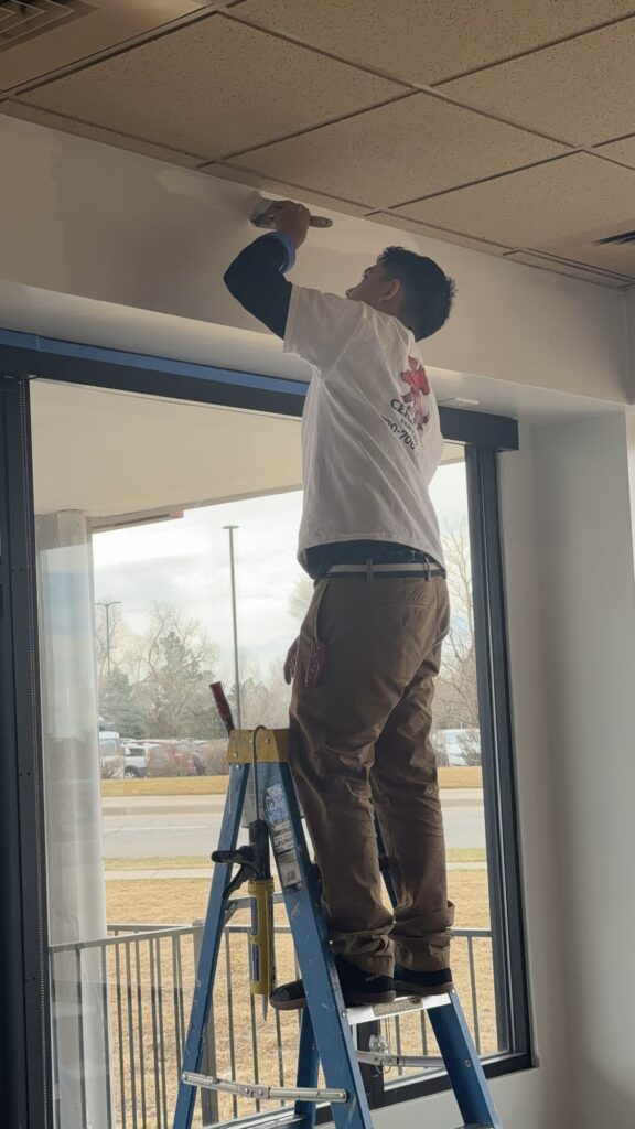 Cerberus Home painter cutting a clean ceiling line in a Denver home